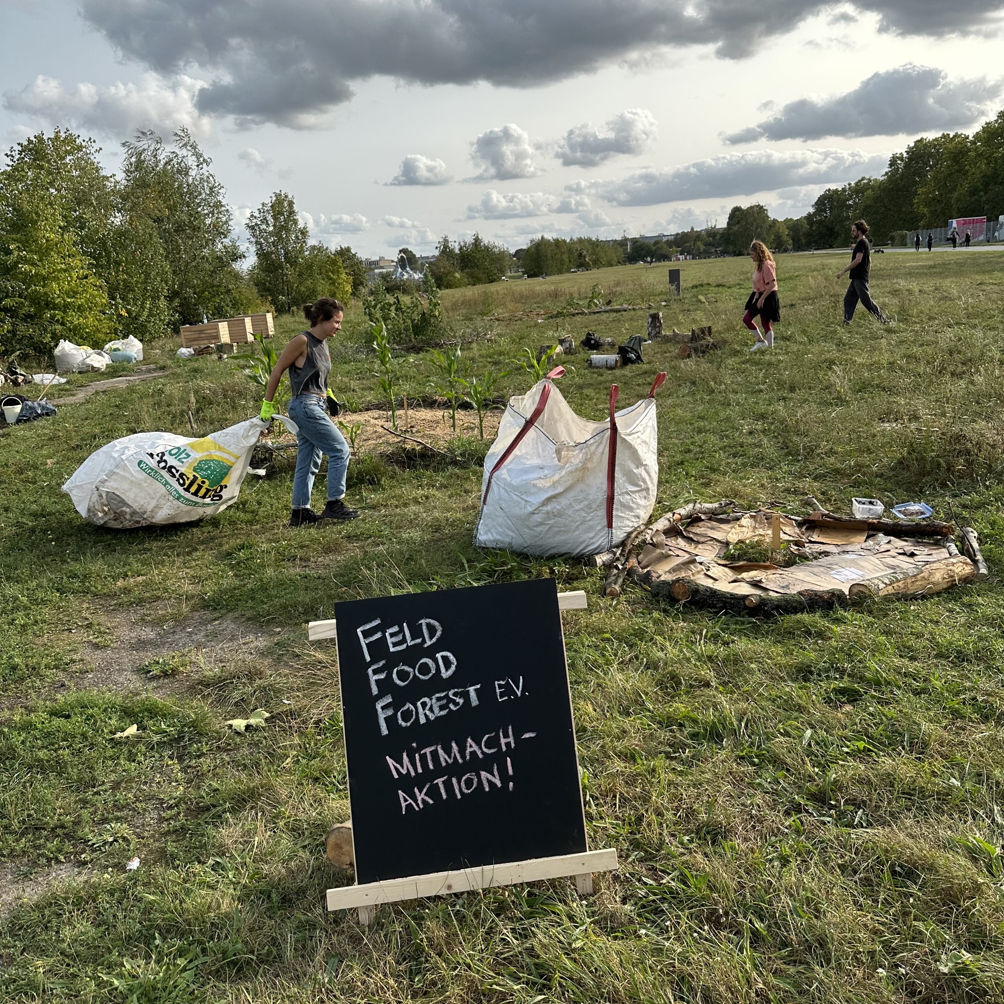 People building beds in a garden. A sign saying "Feld Food Forest".